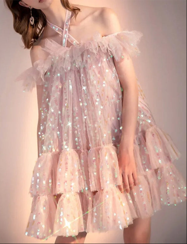 Pink sparkly dress worn by a person on a plain background